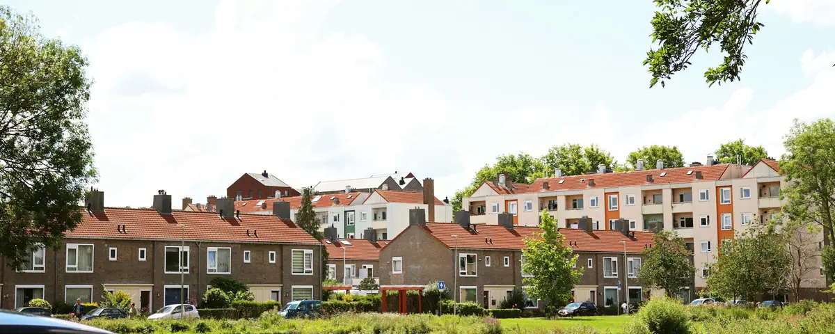 Rijen bakstenen eengezinswoningen en appartementen in een Nederlandse woonwijk