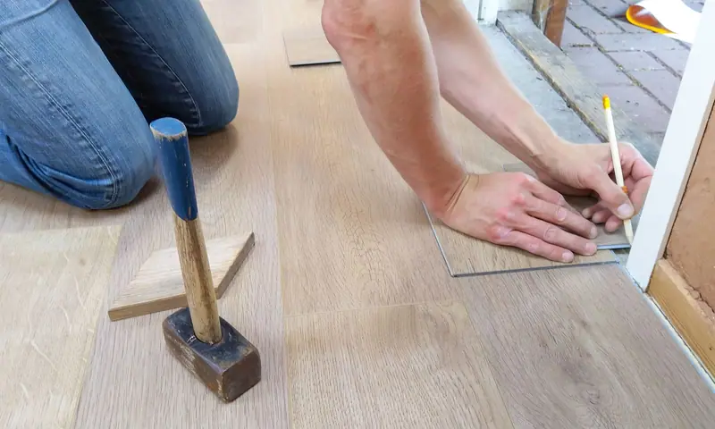 Vloerlegger tekent een vloerplank af bij de deuropening